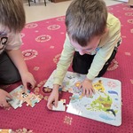 Dzieci wspólnie próbują ułożyć puzzle.jpeg
