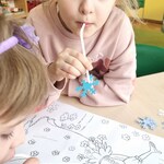 9 Dziewczynka za pomocą słomki zdejmuje papierowe śniezynki z obrazka wiosny.jpg