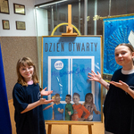 1. Uczennice SU wskazują na plakat powitalny - DZIEŃ OTWARTY - Przyjazna Szkoła.jpg