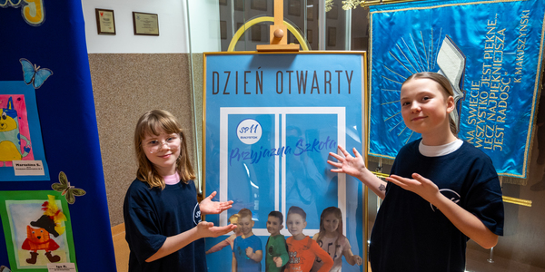 1. Uczennice SU wskazują na plakat powitalny - DZIEŃ OTWARTY - Przyjazna Szkoła.jpg
